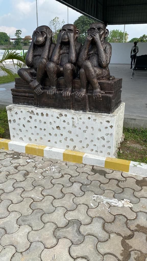 Sculpture of the three wise monkeys seated on a stack of books