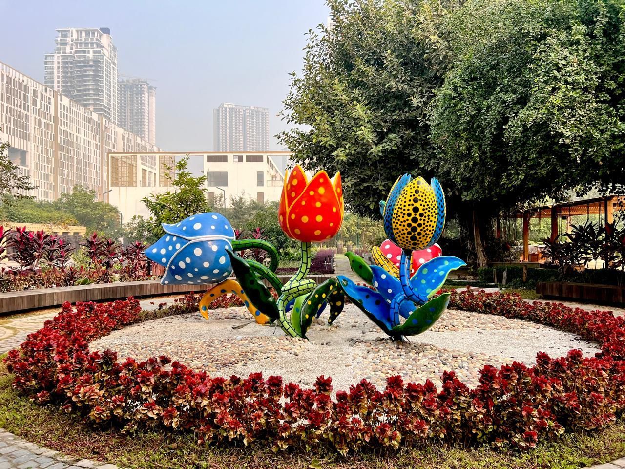 Oversized blue and red spotted tulip sculptures in a circular flower bed