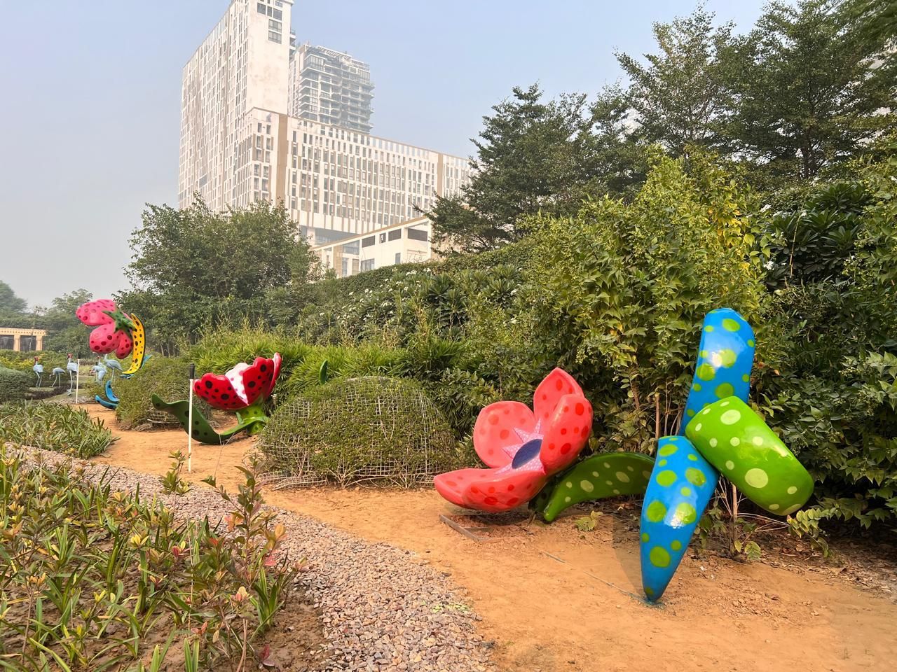Red and spotted flower sculptures along a garden path