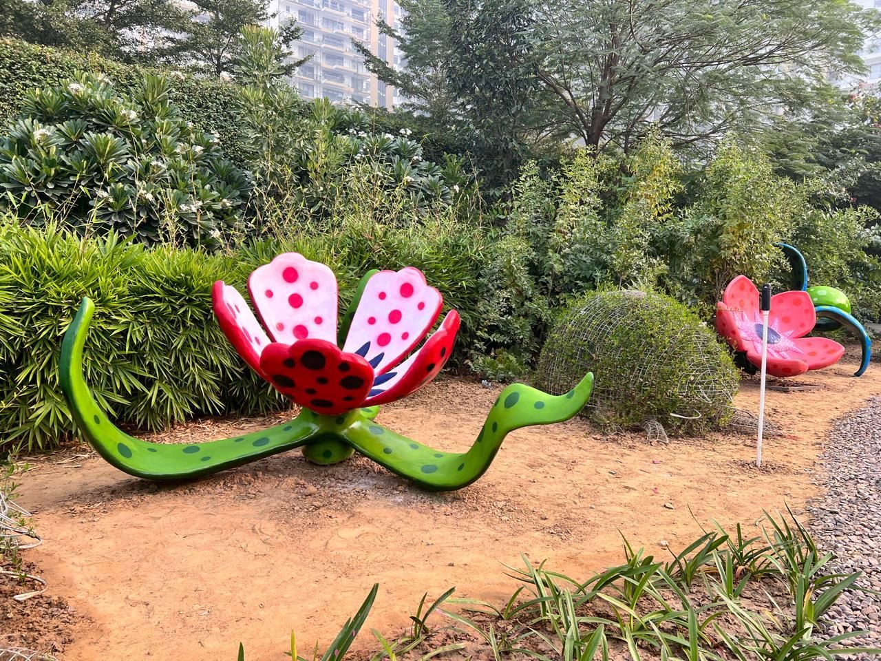 Red flower sculptures with white spots and curling green stems