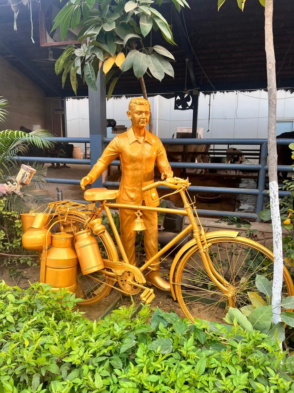 A gold-finish figure of a milkman with his bicycle and milk cans