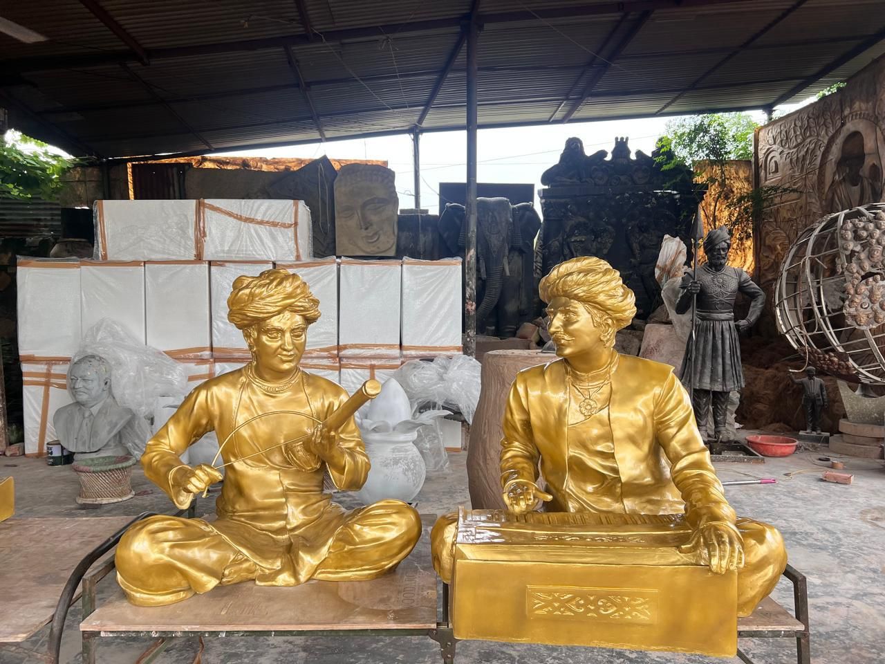 Two gold-finish seated musicians in turbans, one with a stringed instrument, one at a harmonium