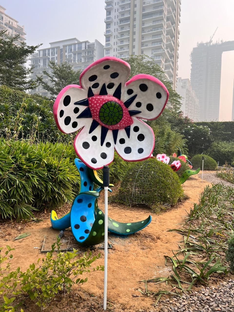 A tall white flower sculpture with black spots and a blue spotted stem