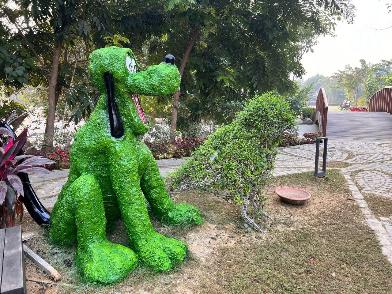 A green grass-finish sculpture of a seated cartoon dog