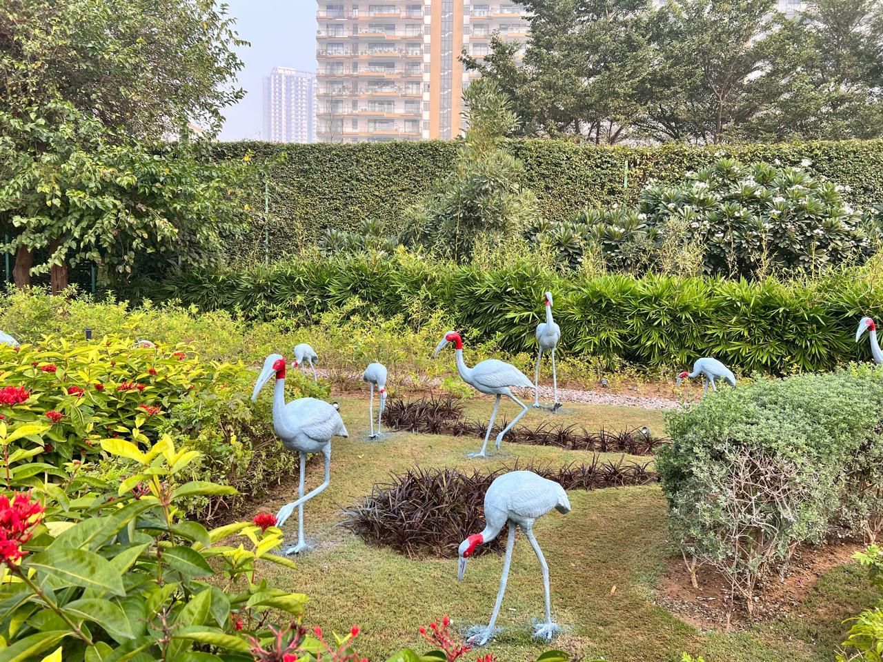 Several crane sculptures around a sunken planted bed