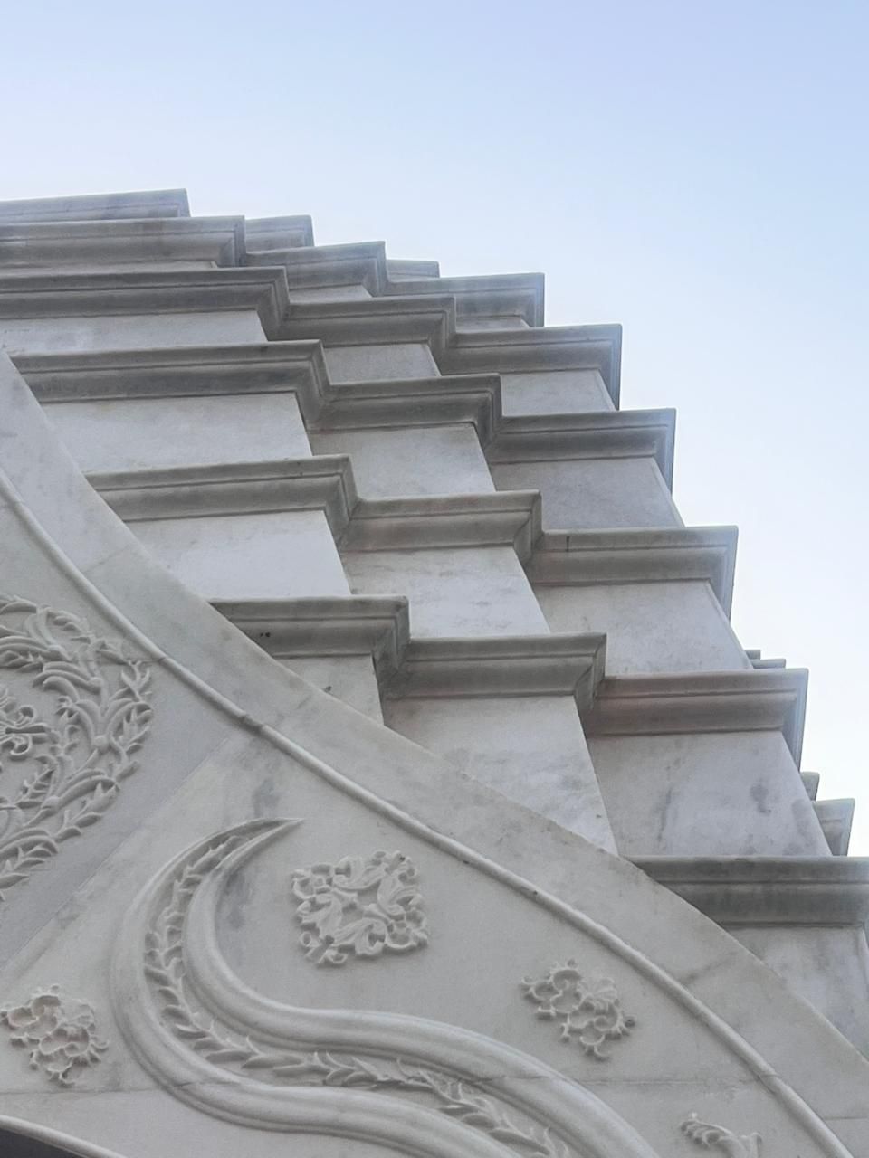 Looking up the stepped marble tiers of the temple spire above a carved gable