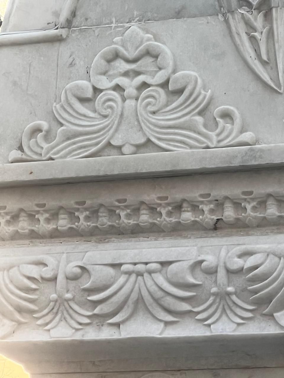 Carved scroll motif and moulded cornice at the top of a marble pillar