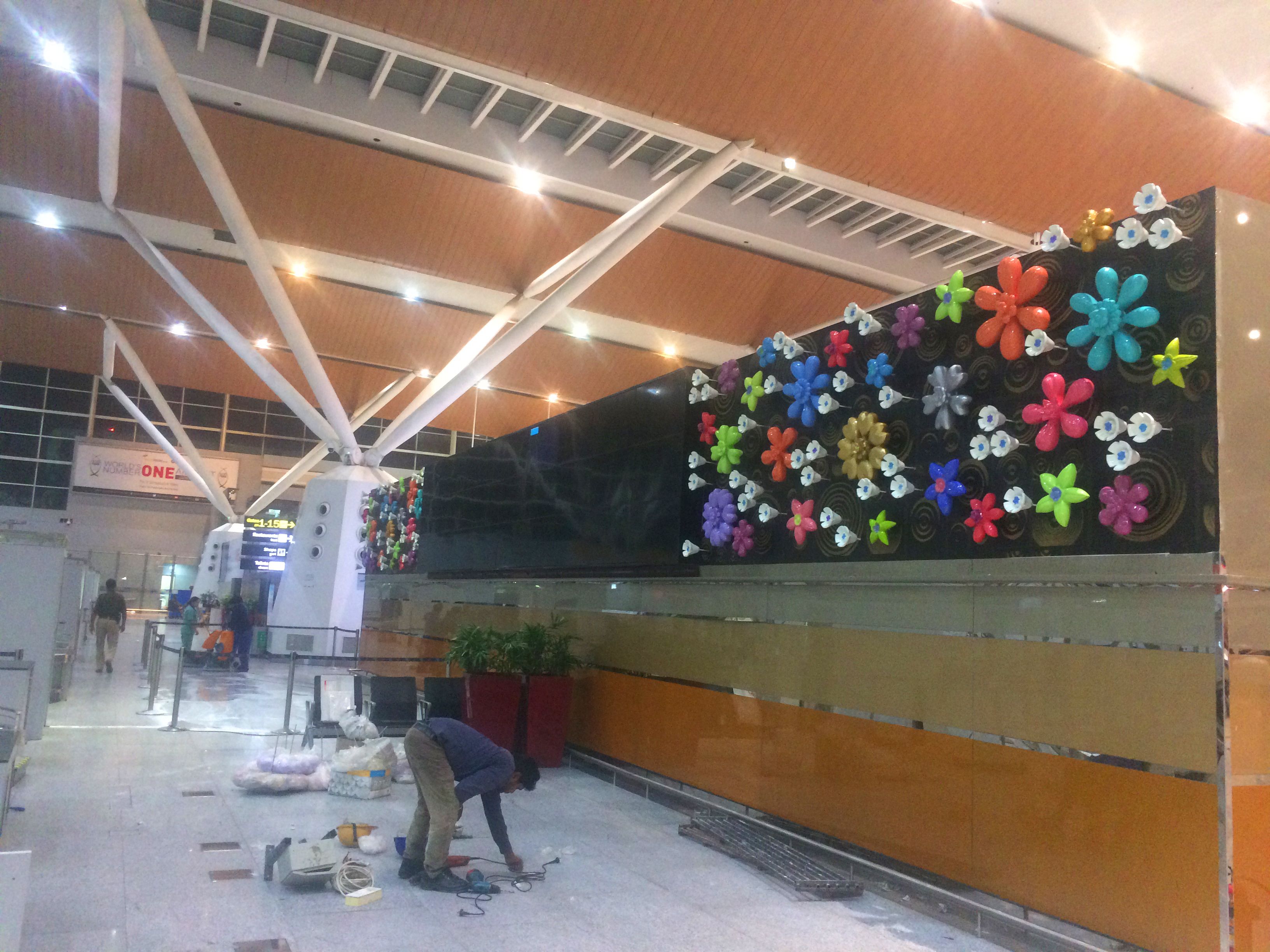 Wall of large colourful sculpted flowers in an airport terminal