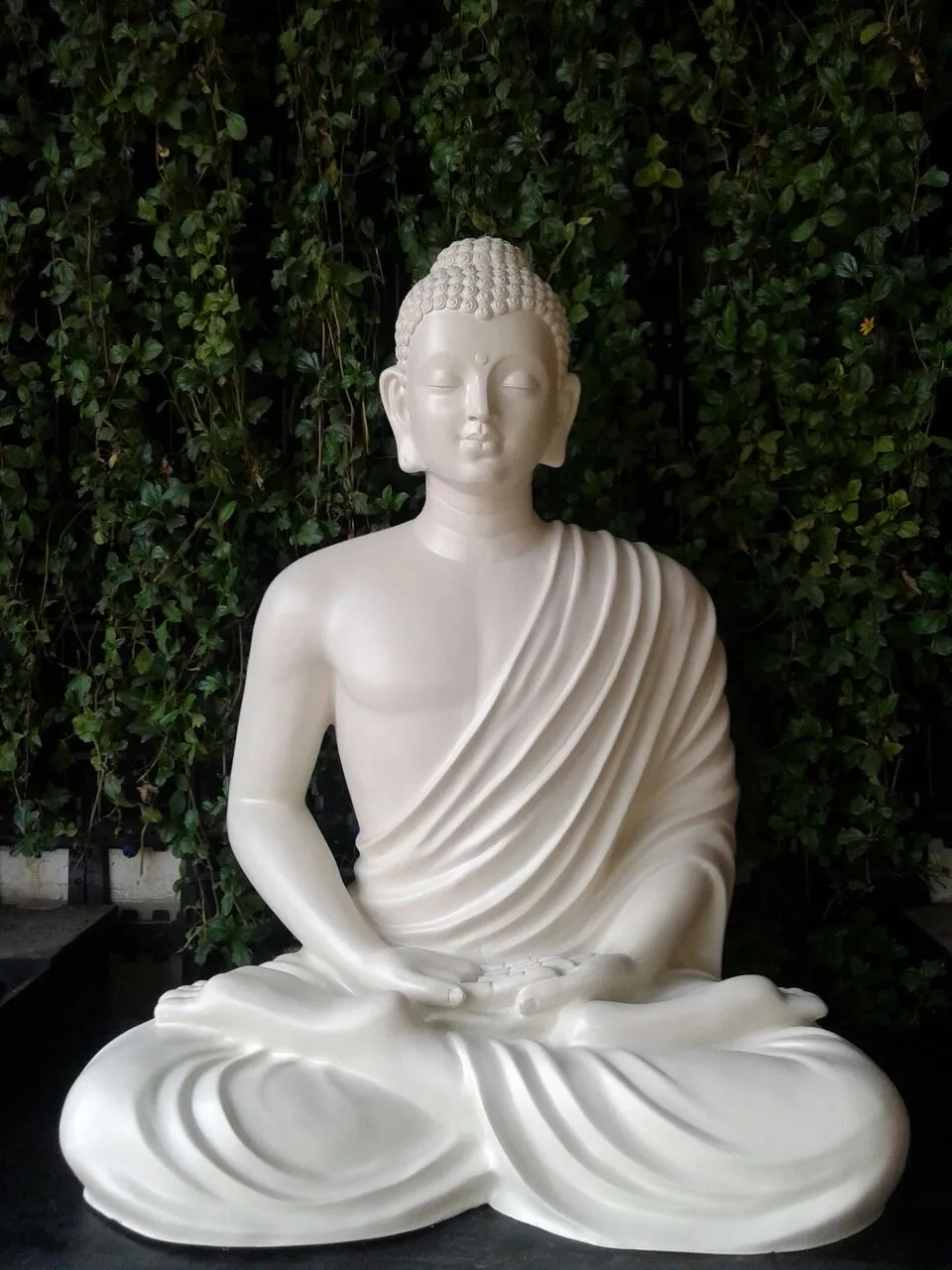 A white seated Buddha in composite