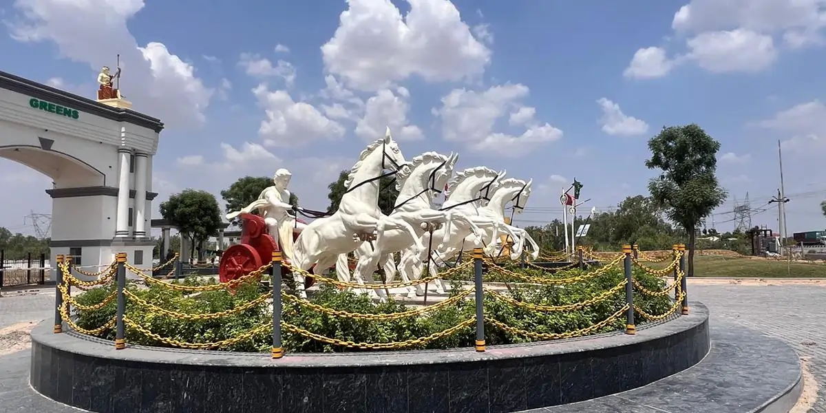 White horses drawing a chariot — a sculpture on a landscaped roundabout